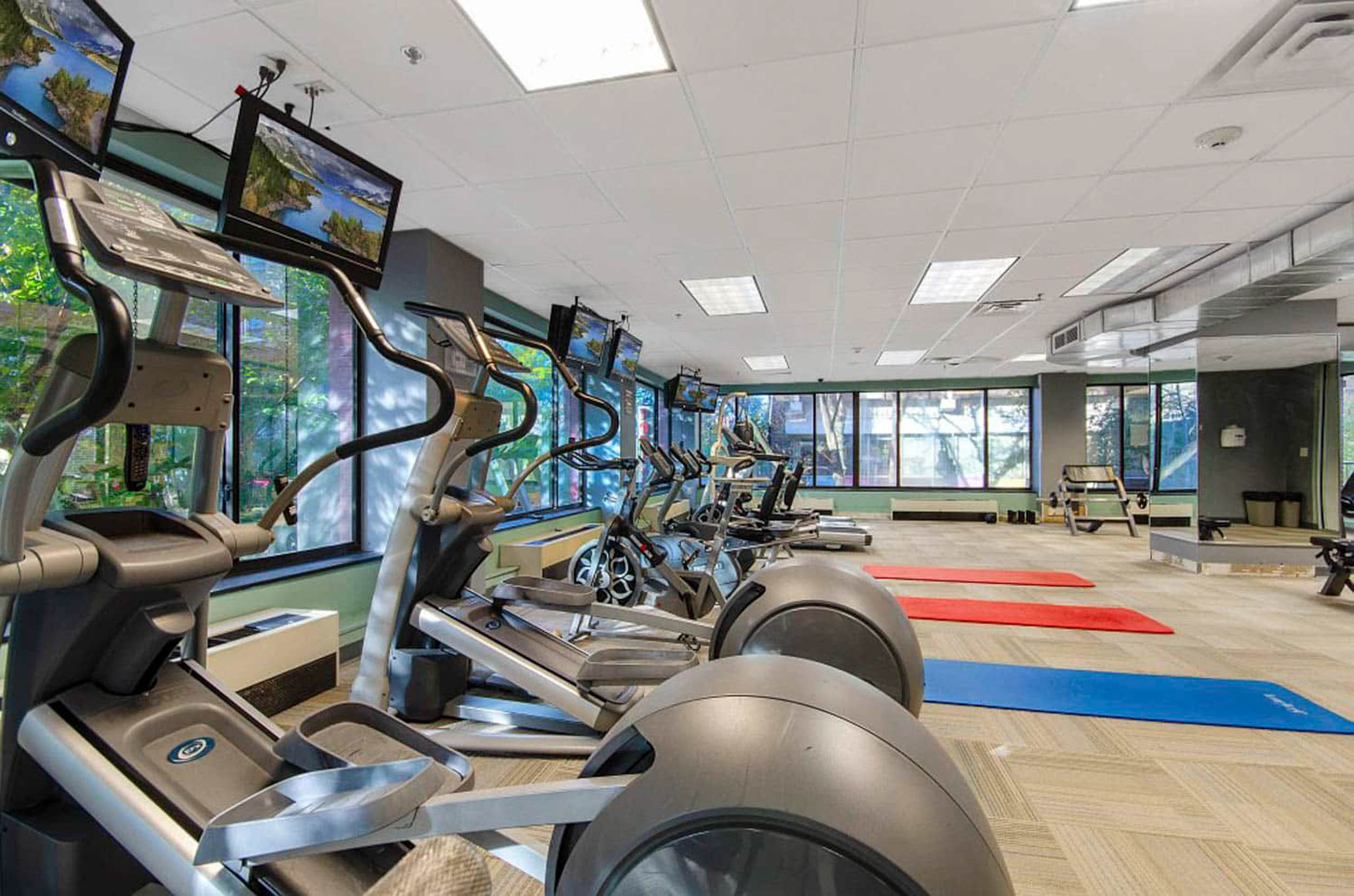 Fitness center with row of exercise machines and workout mats