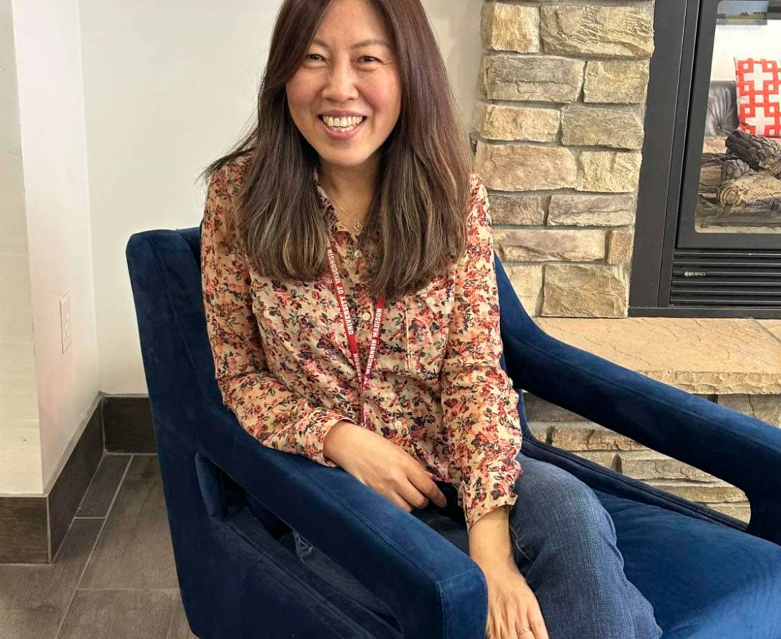 Woman smiling sittnig on blue chair wearing U of W lanyard